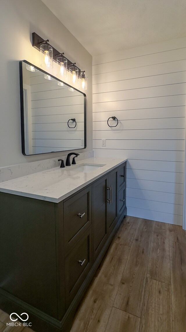 bathroom with vanity, wood-type flooring, and wooden walls