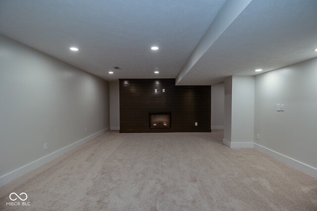 basement featuring a large fireplace and light carpet