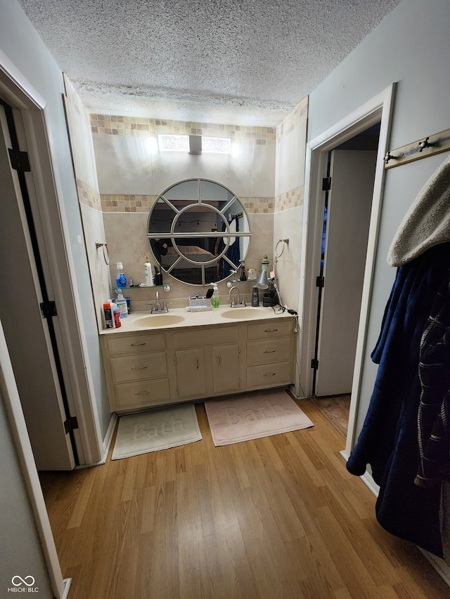 bathroom featuring tile walls, vanity, wood-type flooring, and a textured ceiling