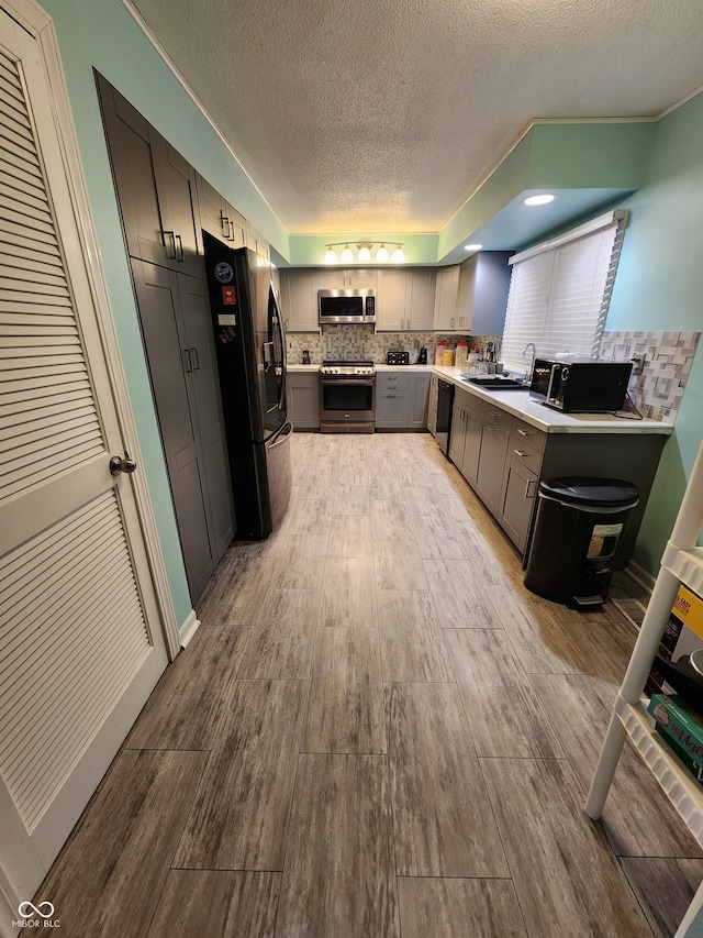 kitchen with sink, gray cabinetry, a textured ceiling, decorative backsplash, and black appliances