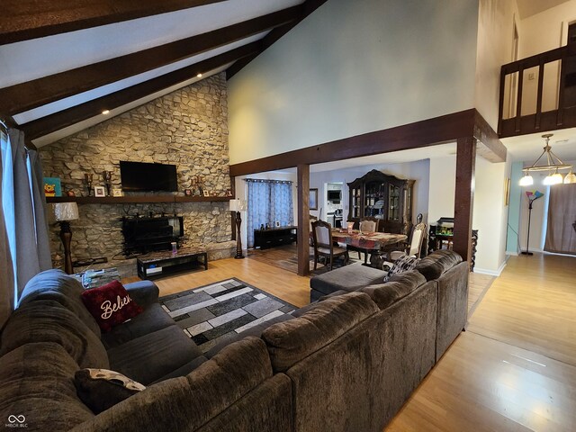 living room with a notable chandelier, high vaulted ceiling, beamed ceiling, and light wood-type flooring