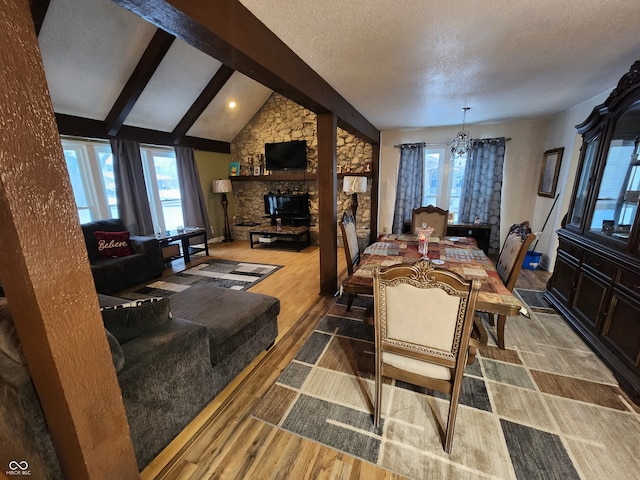 dining room featuring a textured ceiling, wood-type flooring, lofted ceiling with beams, and a healthy amount of sunlight