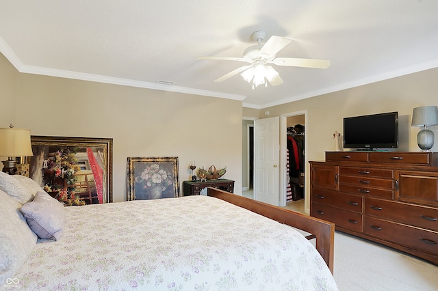 carpeted bedroom featuring a walk in closet, a closet, ceiling fan, and ornamental molding