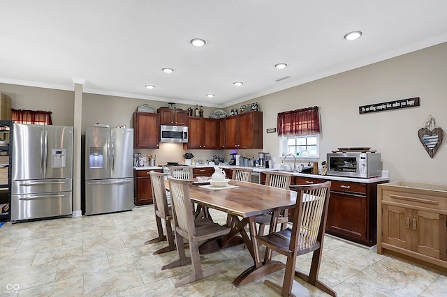 kitchen with appliances with stainless steel finishes, ornamental molding, and sink