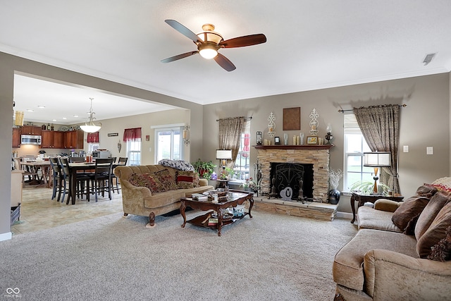 carpeted living room featuring a stone fireplace, a wealth of natural light, crown molding, and ceiling fan