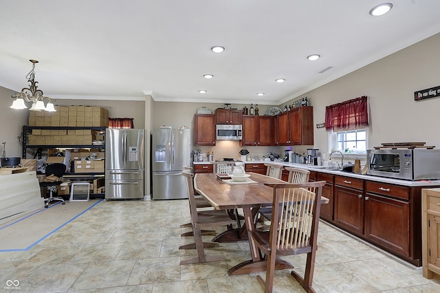 kitchen featuring sink, hanging light fixtures, stainless steel appliances, an inviting chandelier, and ornamental molding