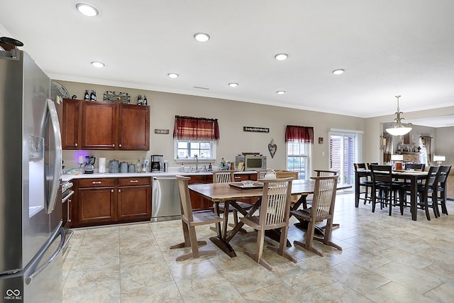 kitchen featuring pendant lighting, crown molding, sink, and stainless steel appliances