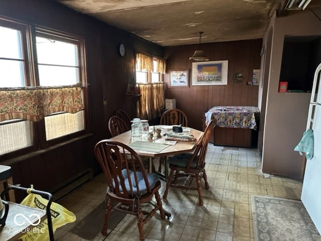 dining space with a baseboard heating unit and wood walls