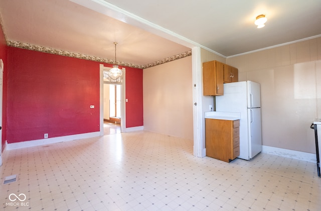 kitchen featuring white refrigerator, an inviting chandelier, hanging light fixtures, and crown molding