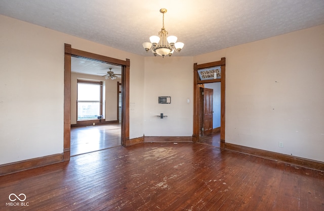 empty room with ceiling fan with notable chandelier, a textured ceiling, and dark hardwood / wood-style floors