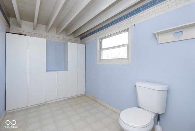 bathroom featuring beamed ceiling and toilet