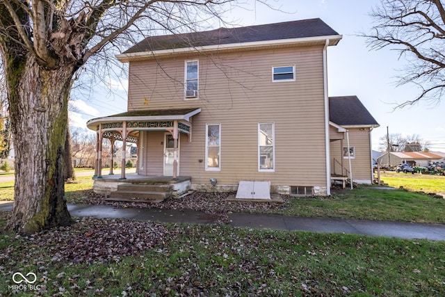 rear view of property featuring a lawn and a porch