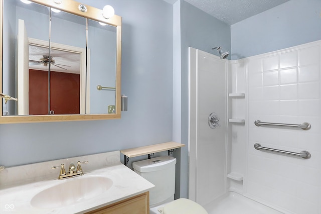 bathroom featuring vanity, ceiling fan, toilet, a textured ceiling, and walk in shower