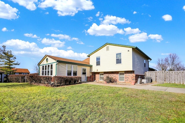 view of front of home with central AC unit and a front yard