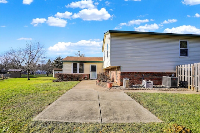 back of house featuring central air condition unit, a patio area, and a lawn