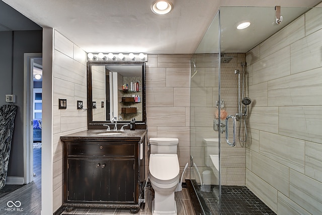 bathroom with an enclosed shower, vanity, hardwood / wood-style flooring, tile walls, and toilet