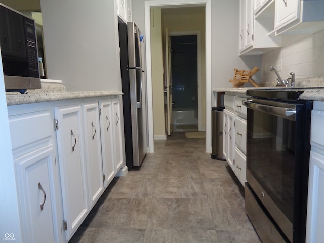 kitchen featuring backsplash, white cabinetry, stainless steel appliances, and light stone counters