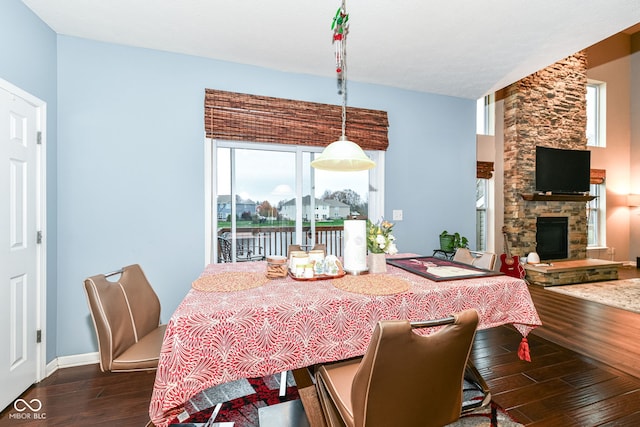 dining space with a stone fireplace and dark hardwood / wood-style flooring