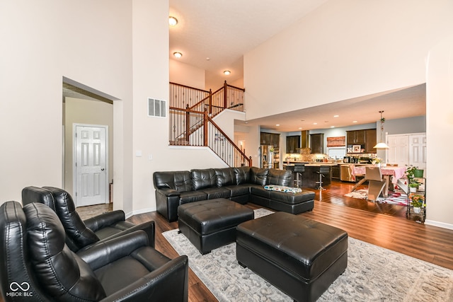 living room with hardwood / wood-style flooring and a towering ceiling