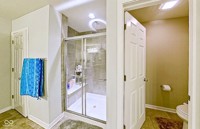 bathroom with a shower with door, a textured ceiling, and toilet