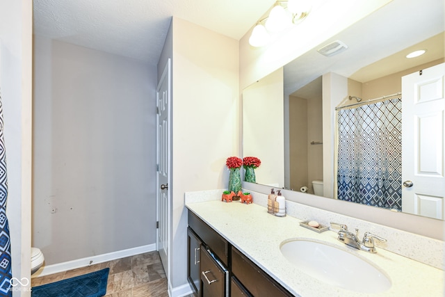 bathroom with vanity, toilet, and a textured ceiling