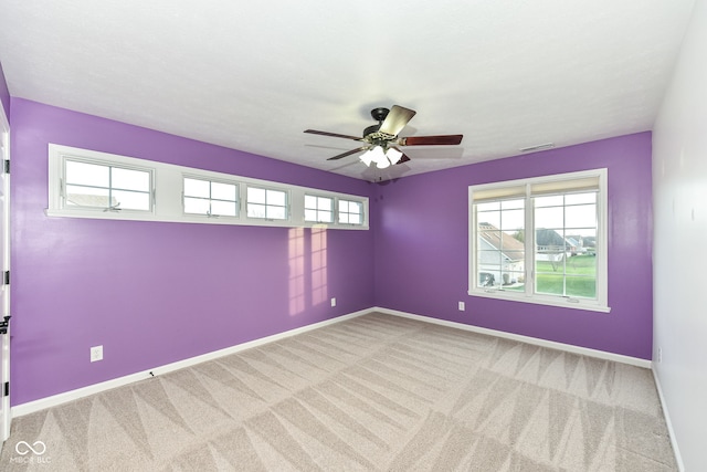 unfurnished room featuring carpet floors, visible vents, baseboards, and a ceiling fan