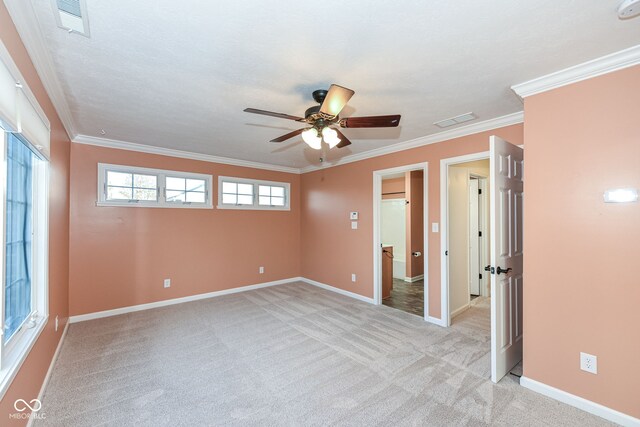 empty room featuring baseboards, ornamental molding, visible vents, and light colored carpet