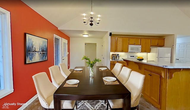 dining space with a chandelier and vaulted ceiling