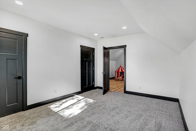 unfurnished bedroom with light colored carpet and lofted ceiling