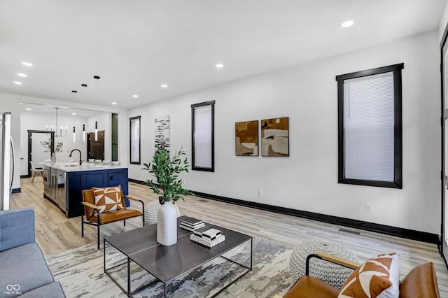 living room featuring light hardwood / wood-style floors, a notable chandelier, and sink