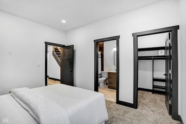 carpeted bedroom featuring ensuite bathroom, a walk in closet, and a closet