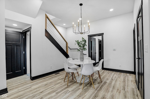 dining area with light hardwood / wood-style floors and a notable chandelier