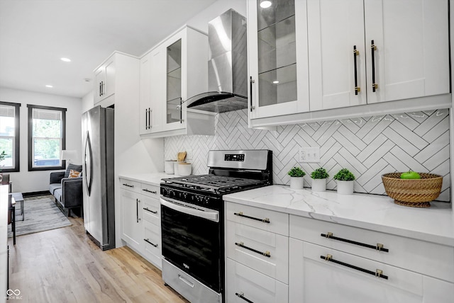 kitchen featuring white cabinets, wall chimney exhaust hood, stainless steel appliances, and light hardwood / wood-style flooring