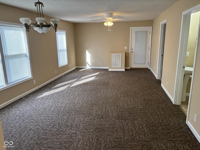 carpeted spare room featuring a textured ceiling and ceiling fan with notable chandelier