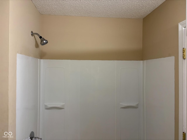 details with a textured ceiling and walk in shower