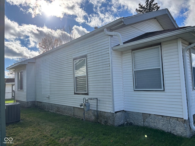 view of side of home featuring cooling unit and a lawn