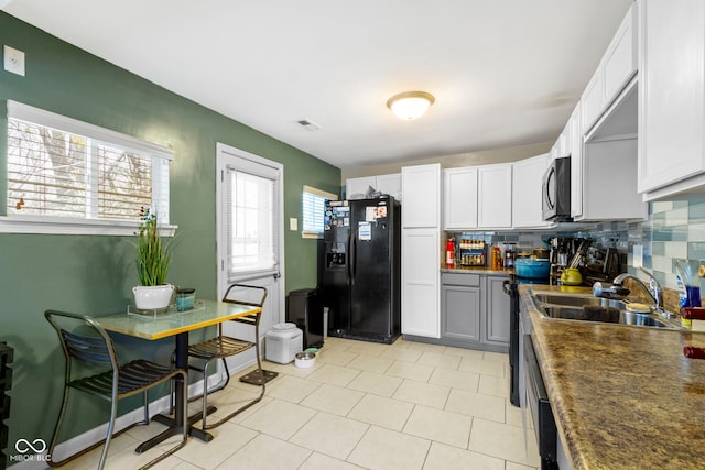 kitchen with white cabinetry, black fridge with ice dispenser, plenty of natural light, and sink