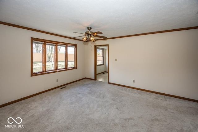 spare room with ceiling fan, crown molding, light colored carpet, and a textured ceiling