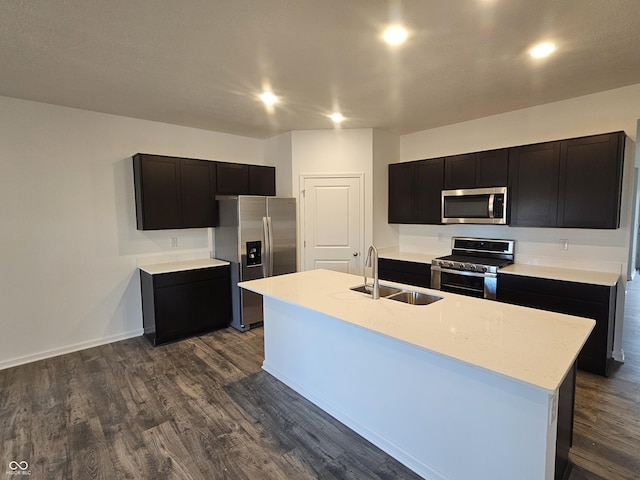 kitchen with dark cabinets, appliances with stainless steel finishes, dark wood finished floors, and a sink