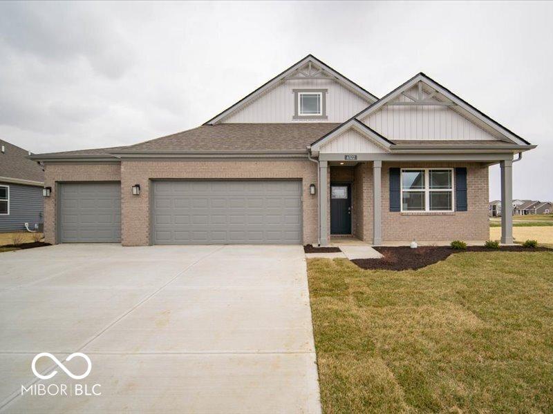 view of front of property with a front yard, an attached garage, brick siding, and concrete driveway