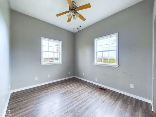 empty room featuring plenty of natural light, ceiling fan, and wood-type flooring