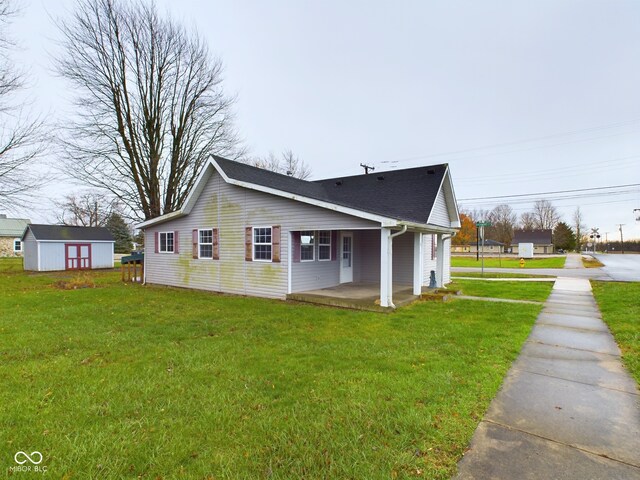31 S Superior St, Orestes, IN 46063 - view of property exterior featuring a porch, a lawn, a storage unit, and a shingled roof