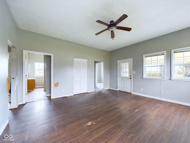 unfurnished living room featuring dark hardwood / wood-style flooring, ceiling fan, and a healthy amount of sunlight