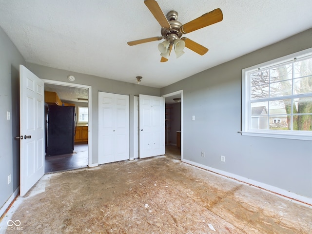 unfurnished bedroom featuring black refrigerator, a textured ceiling, and ceiling fan