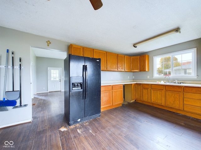 kitchen with dark wood-type flooring, black refrigerator with ice dispenser, sink, ceiling fan, and a textured ceiling