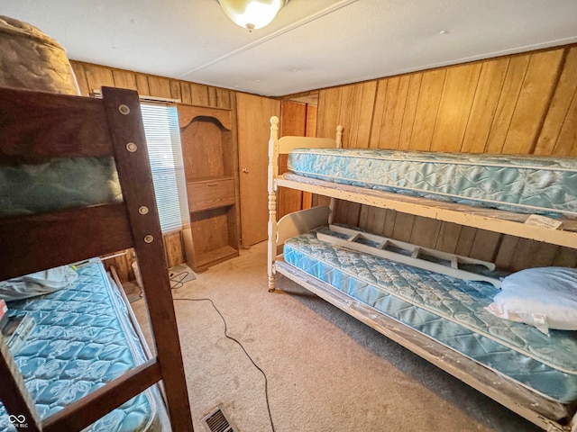 bedroom featuring wood walls and light colored carpet