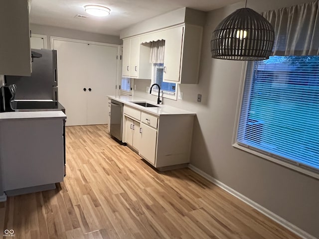 kitchen featuring hanging light fixtures, sink, stainless steel appliances, and light wood-type flooring