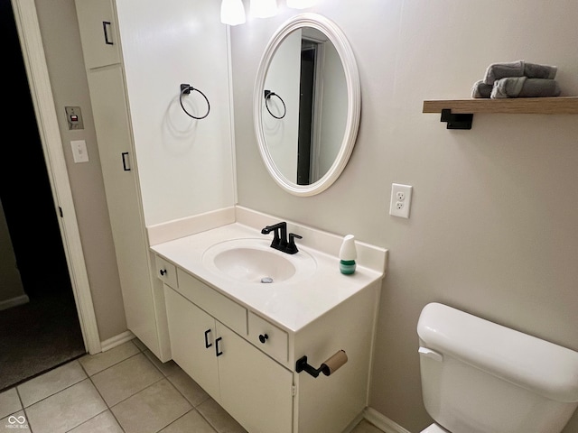 bathroom with toilet, vanity, and tile patterned floors