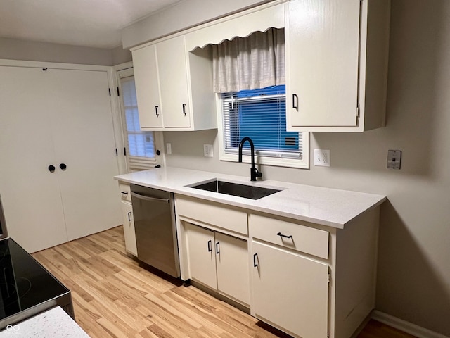 kitchen featuring white cabinetry, sink, stainless steel dishwasher, and light wood-type flooring