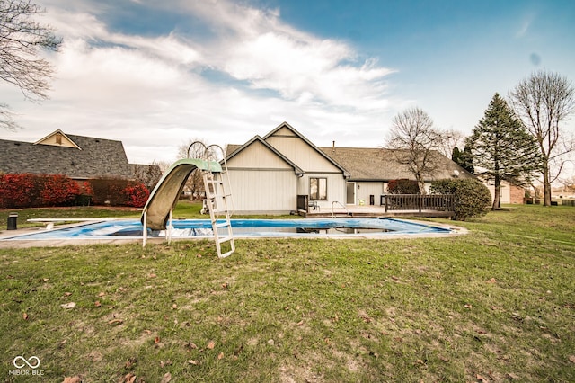 view of swimming pool with a diving board, a yard, and a water slide